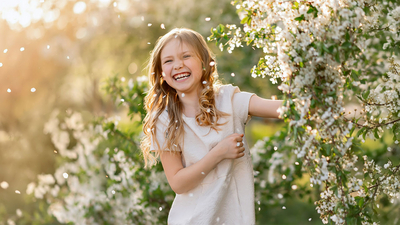 Freudestrahlendes Kind vor einem Strauch voller Blüten