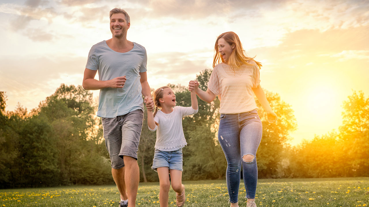 Glückliche Familie läuft händchenhaltend über eine Wiese