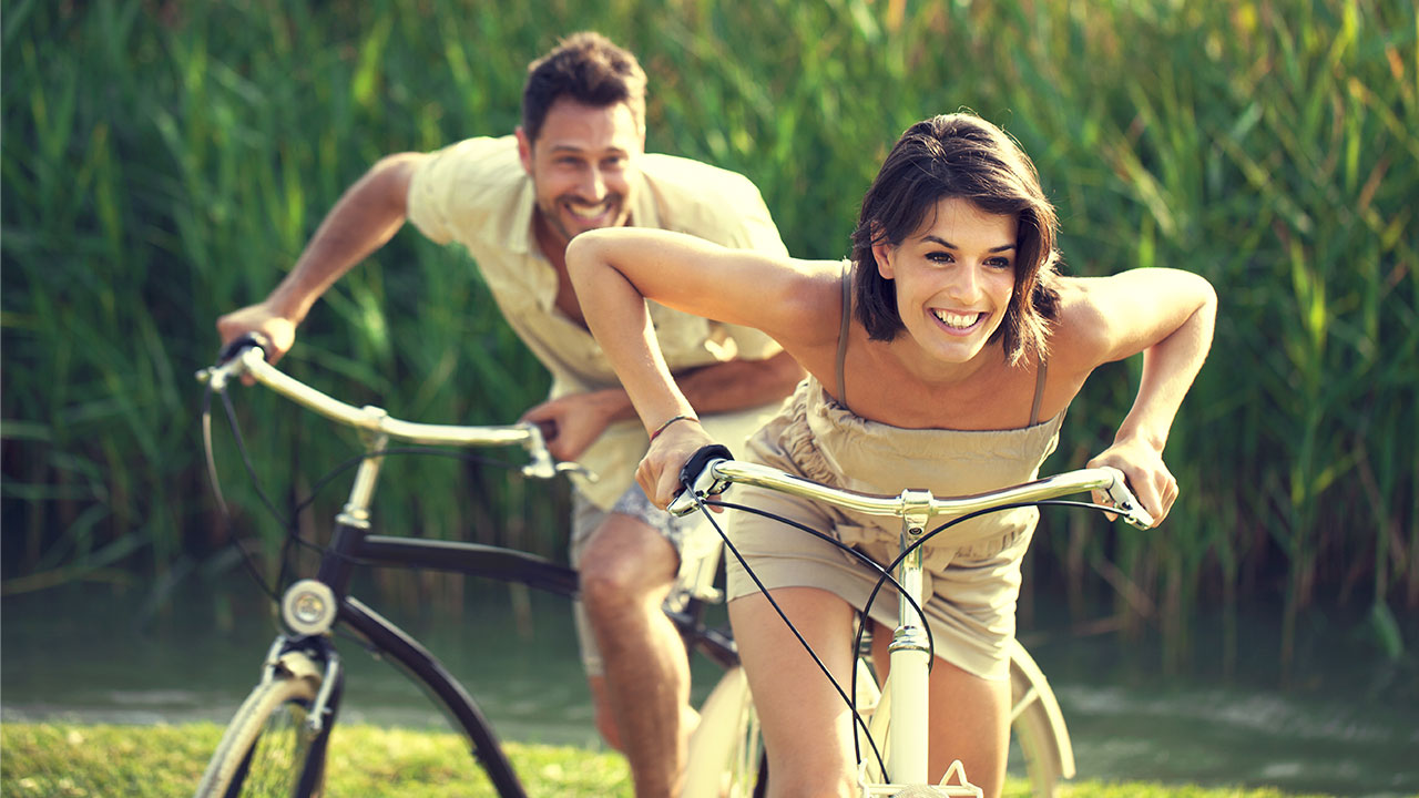 Einfach sparen Lachendes Pärchen auf Fahrrädern