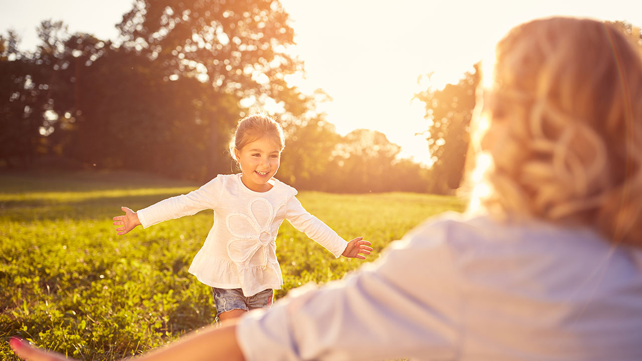 Nachhaltig anlegen Glückliches Kind läuft in die offenen Arme ihrer Mutter