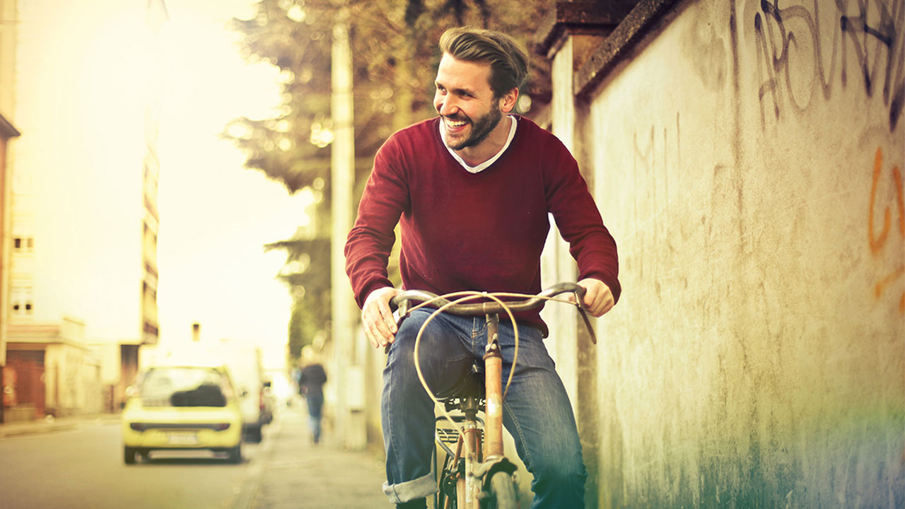 Einfach Fondssparen Lächelnder Mann auf Fahrrad