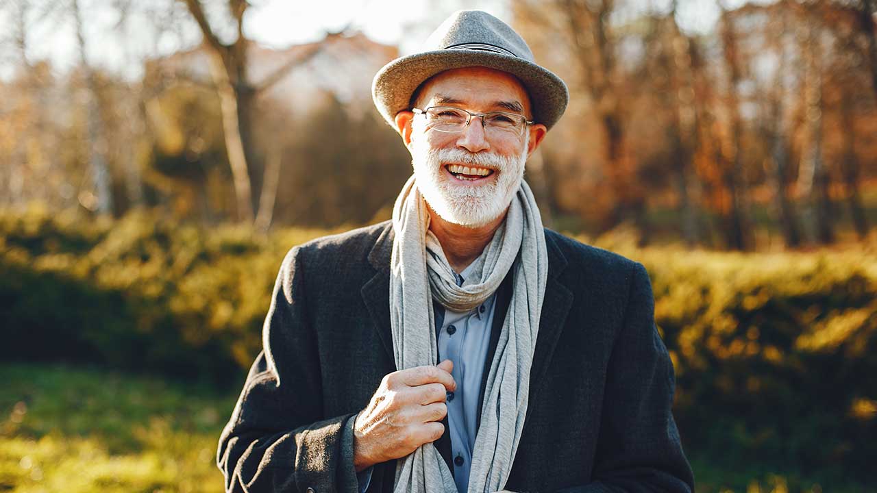 Vermögen investieren Lächelnder älterer Mann mit Hut und Schal