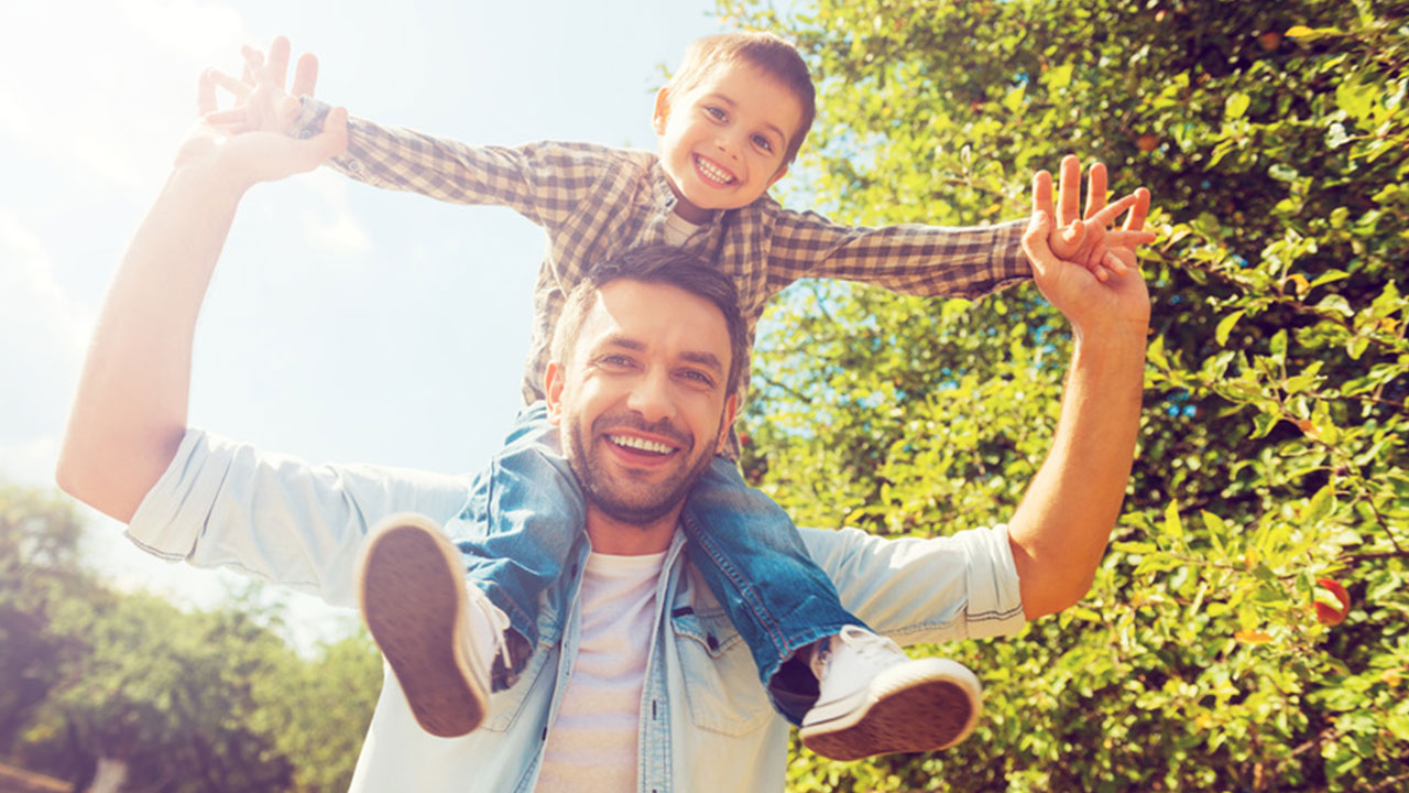 Vater trägt lachenden Sohn auf den Schultern