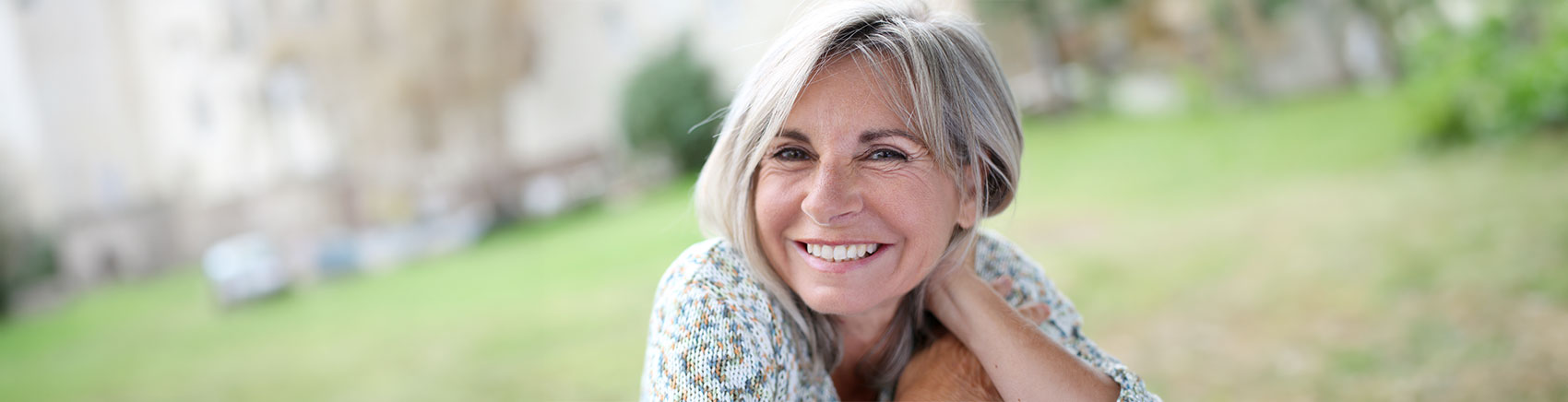 Strahlende ältere Frau liegt auf einer Wiese