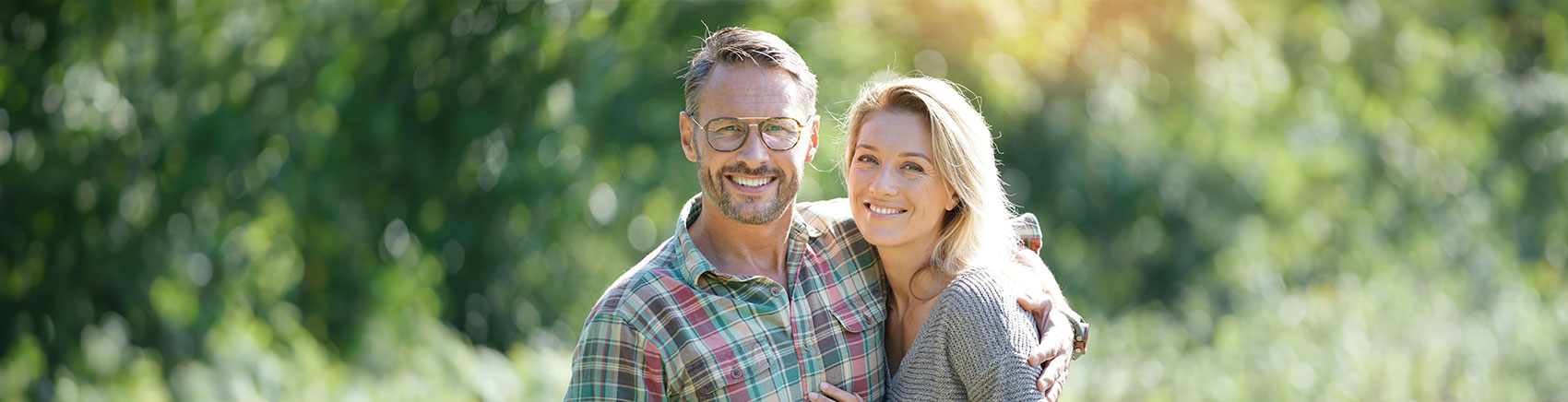 Lächelndes älteres Pärchen umarmt sich auf einer Wiese