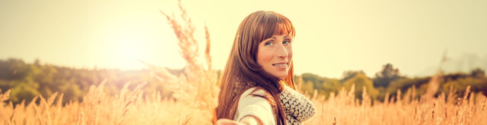 Frau in einem Weizenfeld hält eine Weizenähre in der Hand
