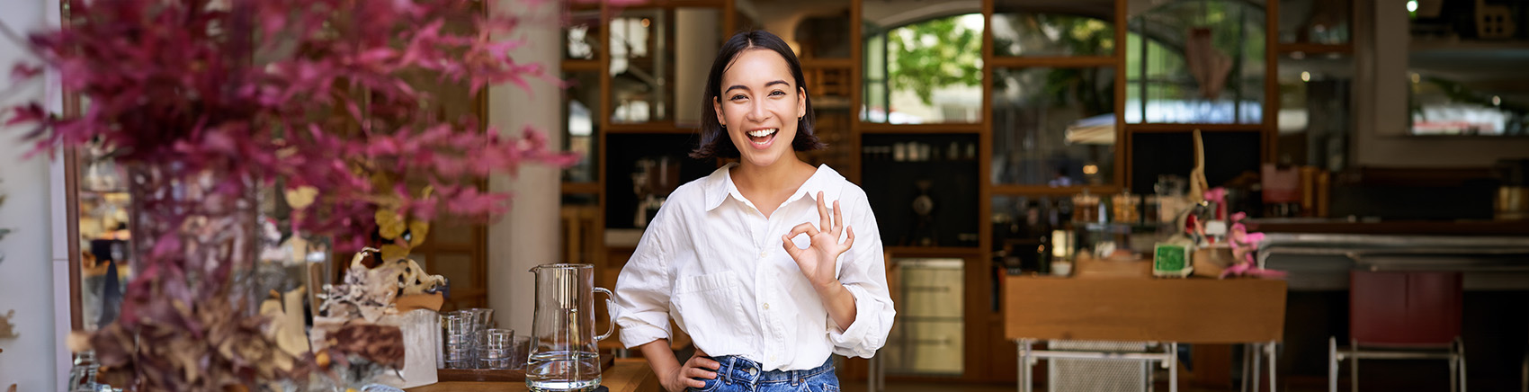 Lächelnde Frau macht ein Ok-Handzeichen, um ihre Zufriedenheit mit den Anlagemöglichkeiten zu zeigen