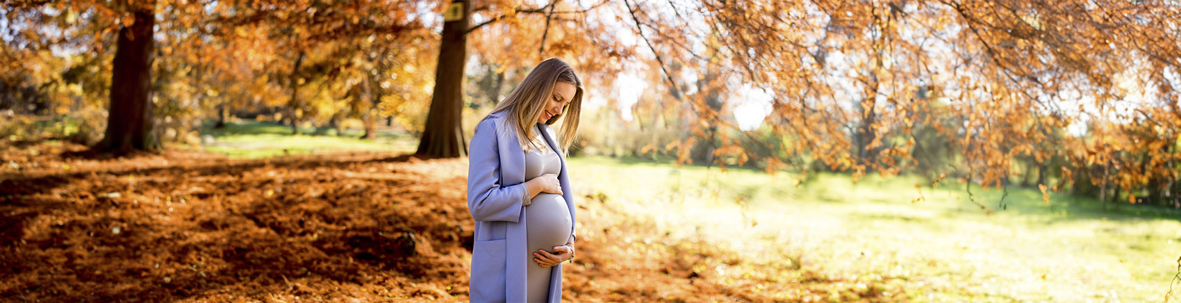 Schwangere Frau blickt lächelnd auf Ihren Babybauch