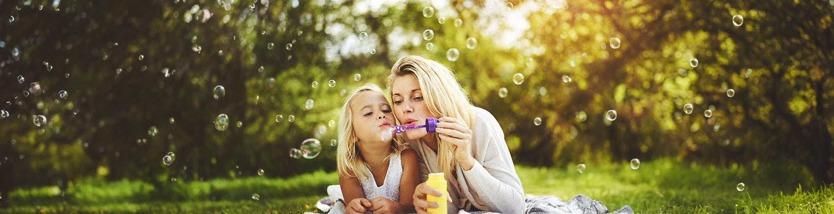 Mutter und Tochter spielen mit Seifenblasen