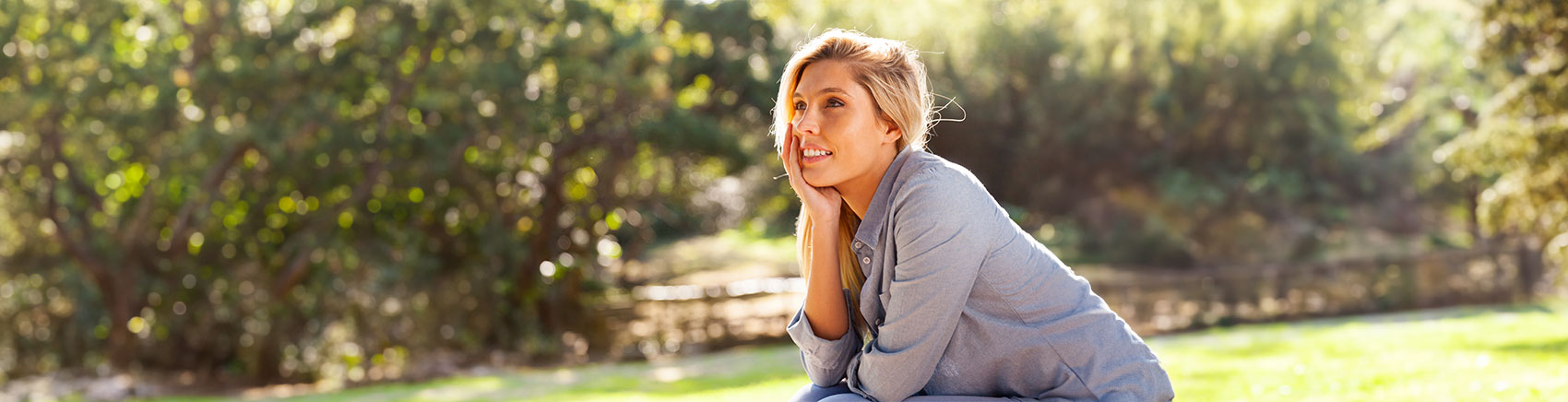 Frau sitzt nachdenklich in einem Park